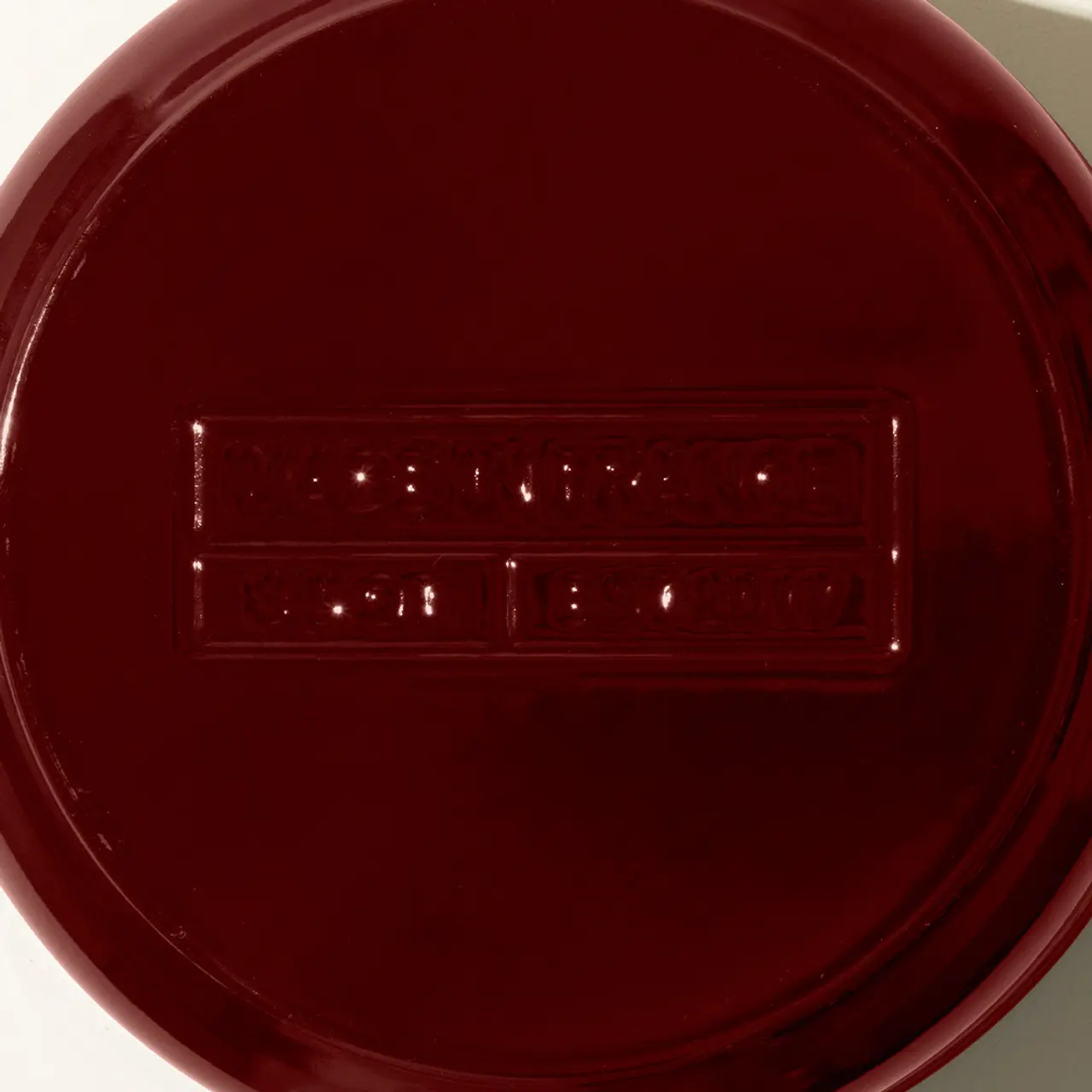 Overhead view of a red Petri dish with bacterial colonies growing in the shape of a braille inscription.