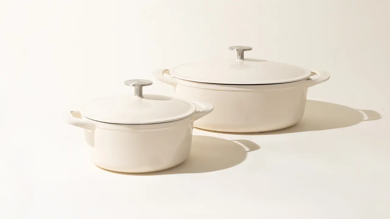 Two off-white ceramic pots with lids on a neutral background, varying in size, casting soft shadows to the right.