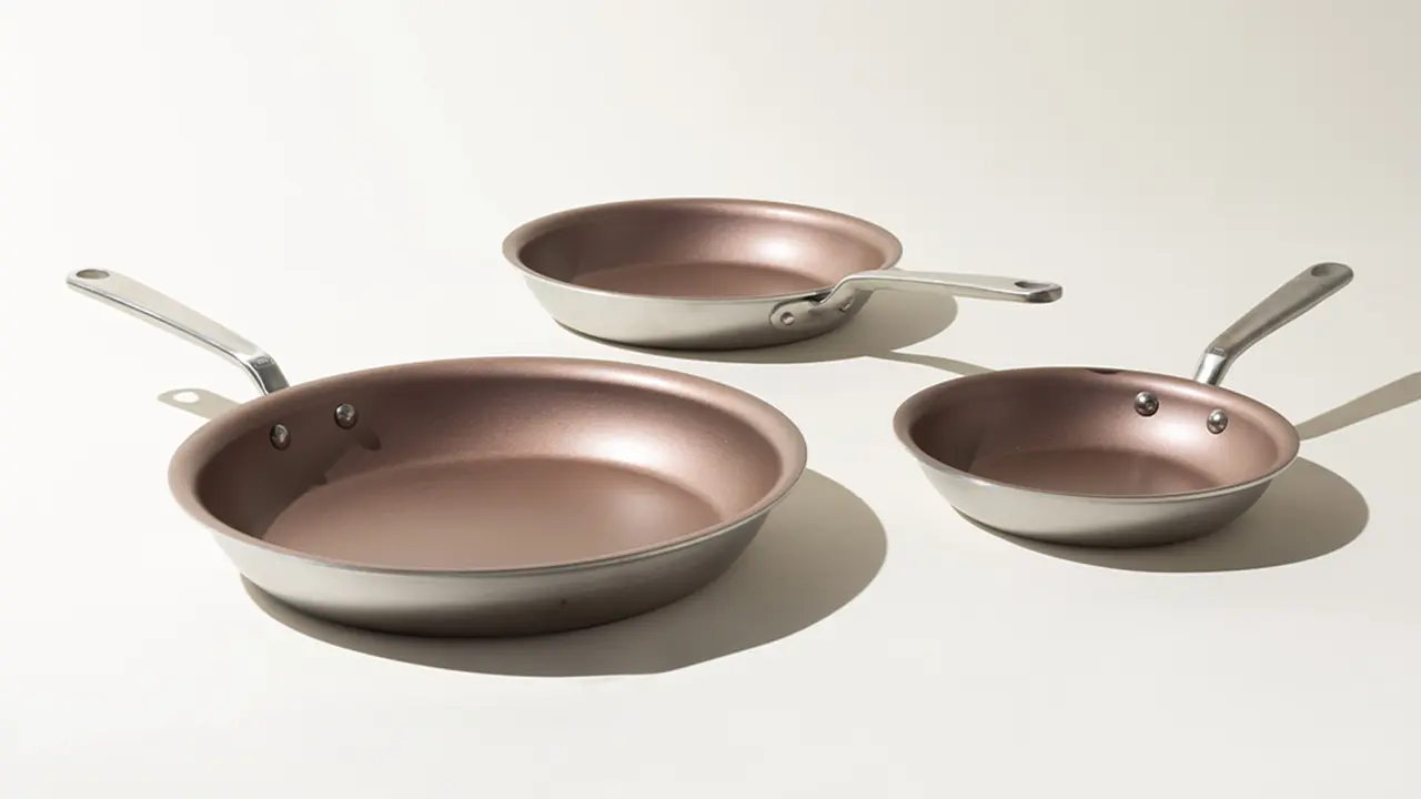 Three different-sized copper-colored pans are arranged in a row on a light surface.