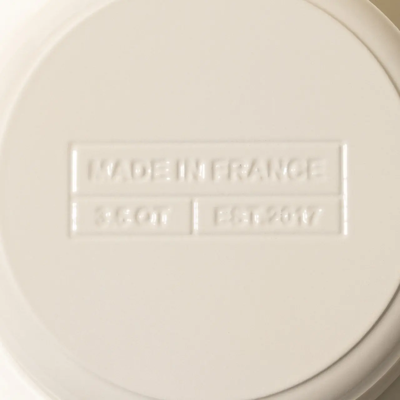 Close-up of the embossed bottom of a porcelain item with "Made in France" and additional markings indicating size and model year.